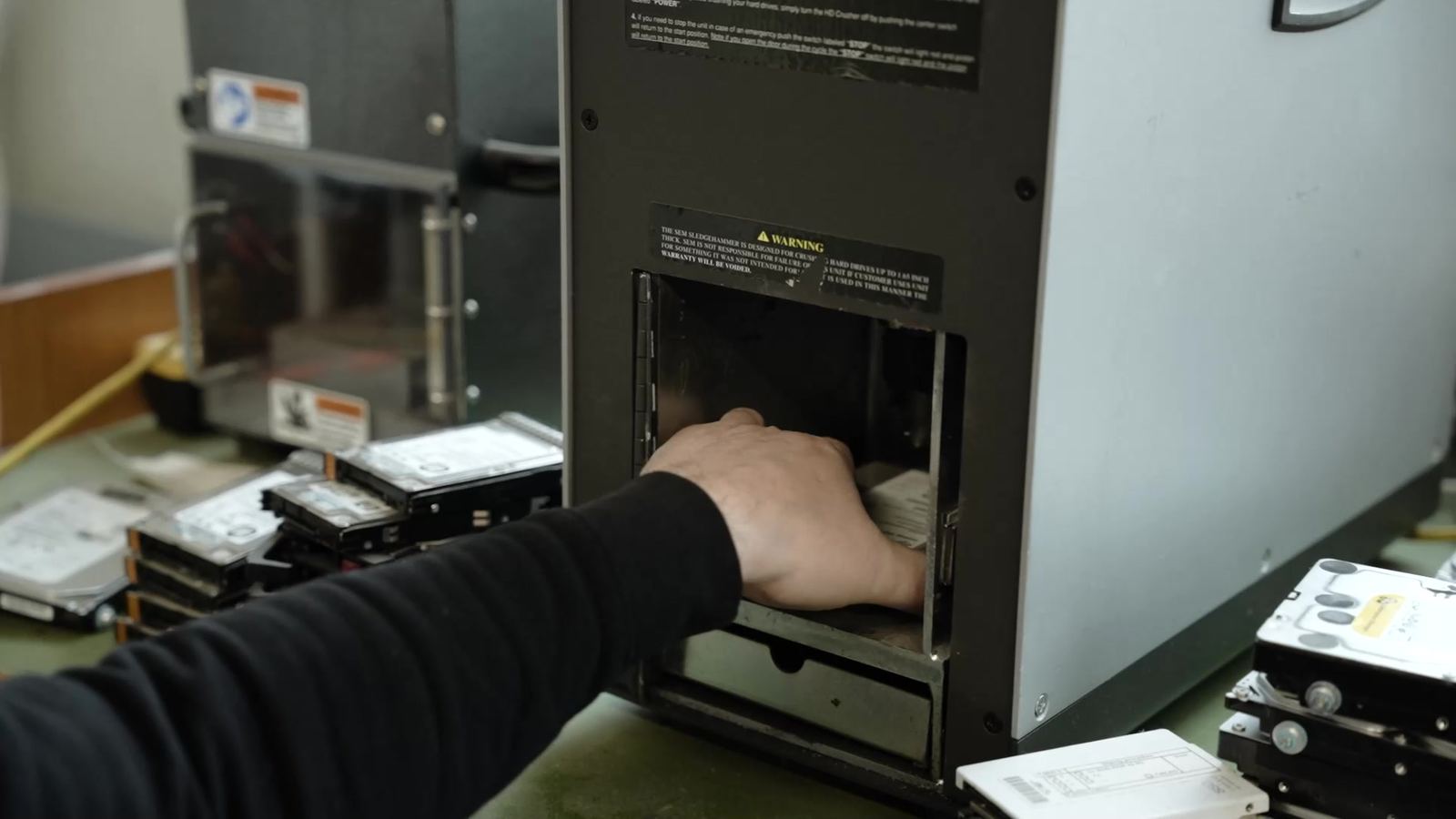 An employee places a hard drive into the destruction machine