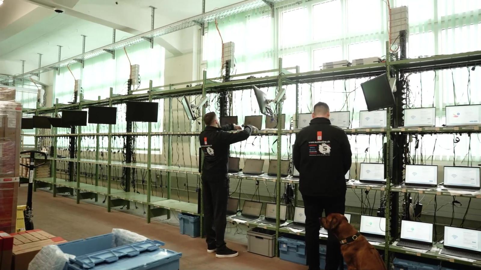 Two technicians set up laptops in the staging cages